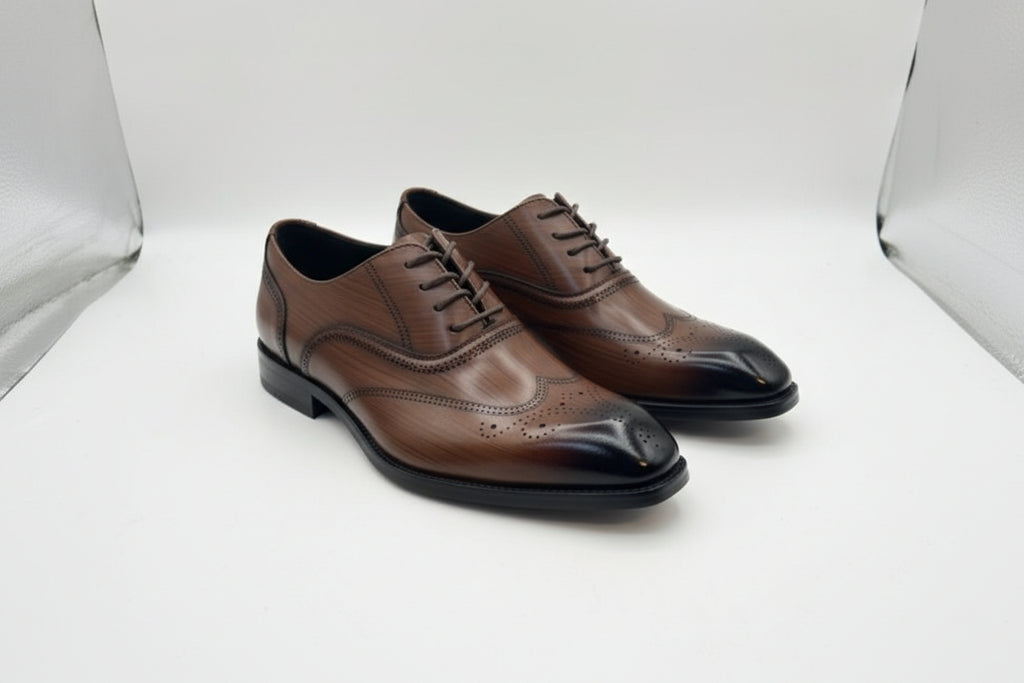 Brown dress shoe held by a hand with a brand box in the background