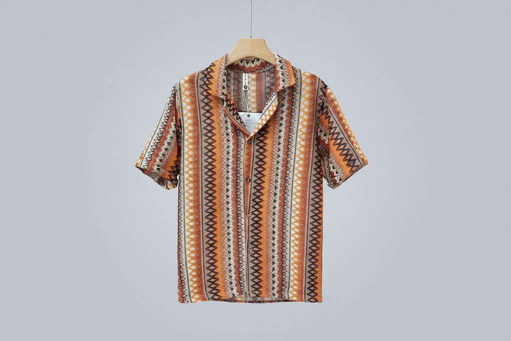 Short-sleeve patterned shirt held by a hand against a blurred background