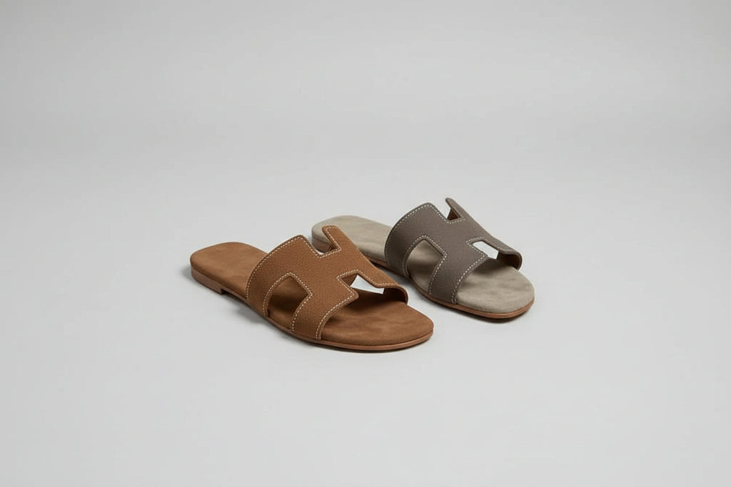 Pair of brown sandals on a wooden surface with a white paper underneath.