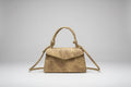 Gold handbag with a strap on a white surface
