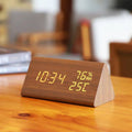 Wooden digital clock with time, temperature, and humidity display on a wooden surface.