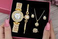 Gold jewelry set including watch, bracelet, necklace, and earrings on a black background.