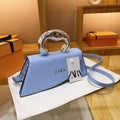 Blue Zara handbag with a silver handle on a white surface.