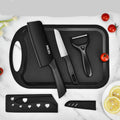Black kitchen utensils set on a tray with tomatoes and lemon slices on a marble background