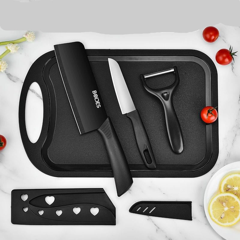 Black kitchen utensils set on a tray with tomatoes and lemon slices on a marble background