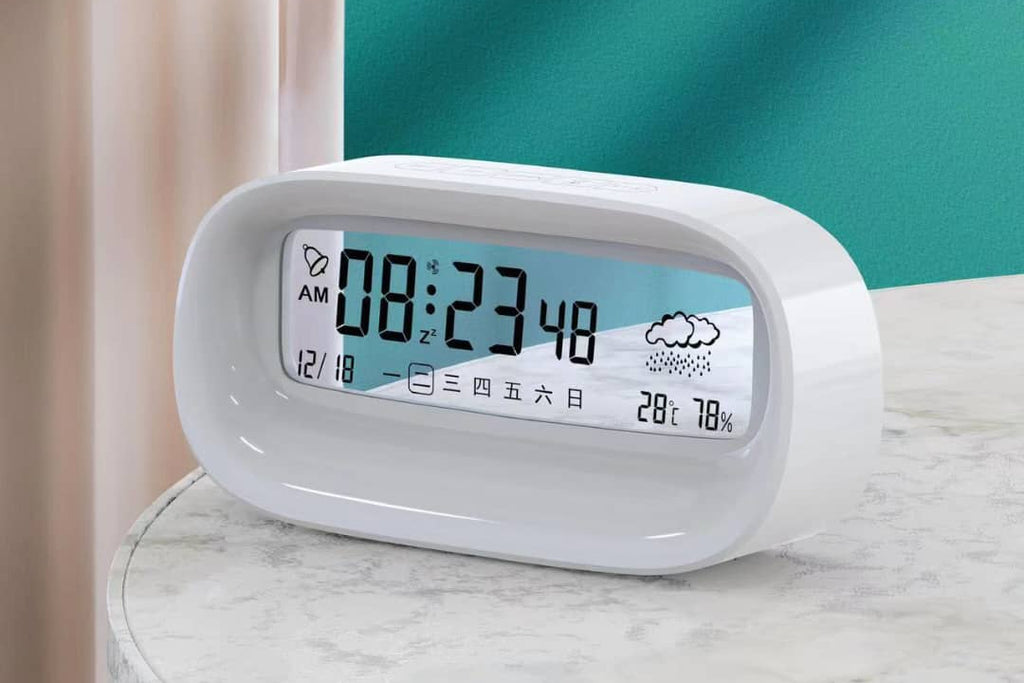 Digital alarm clock with time and weather display on a marble surface.