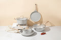 Set of ceramic cookware with sizes and measurements indicated on a beige background