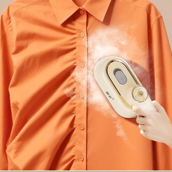 Hand holding a handheld steamer on an orange shirt with text describing the product's features.