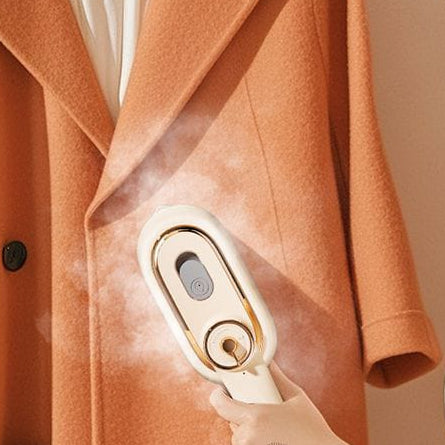 Woman using a garment steamer on an orange coat with text in Chinese.