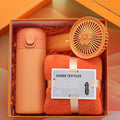 Orange home textiles set with a thermos, towel, and fan in an open box.
